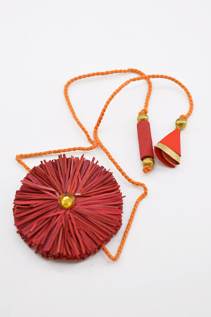 A red circular paper fan necklace with a braided orange cord, gold bead accents, and a small red and gold tassel, displayed on a clean white background.